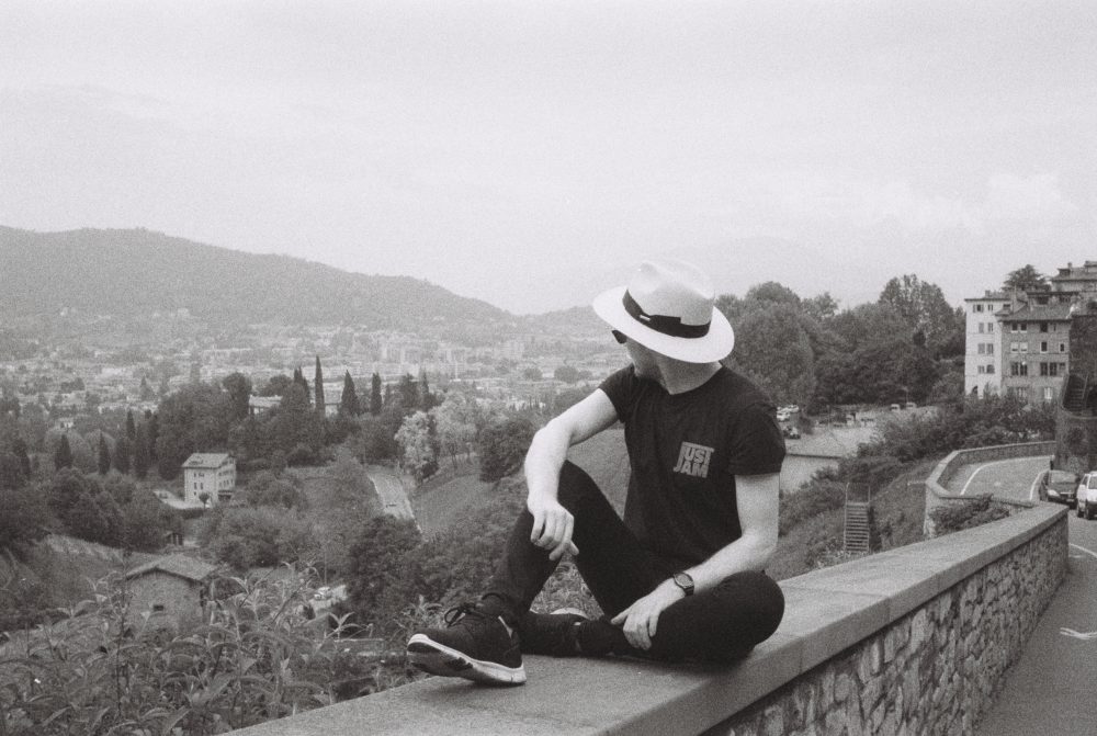 A photo of coxy sitting on a wall overlooking the landscape of Bergamo, Italy