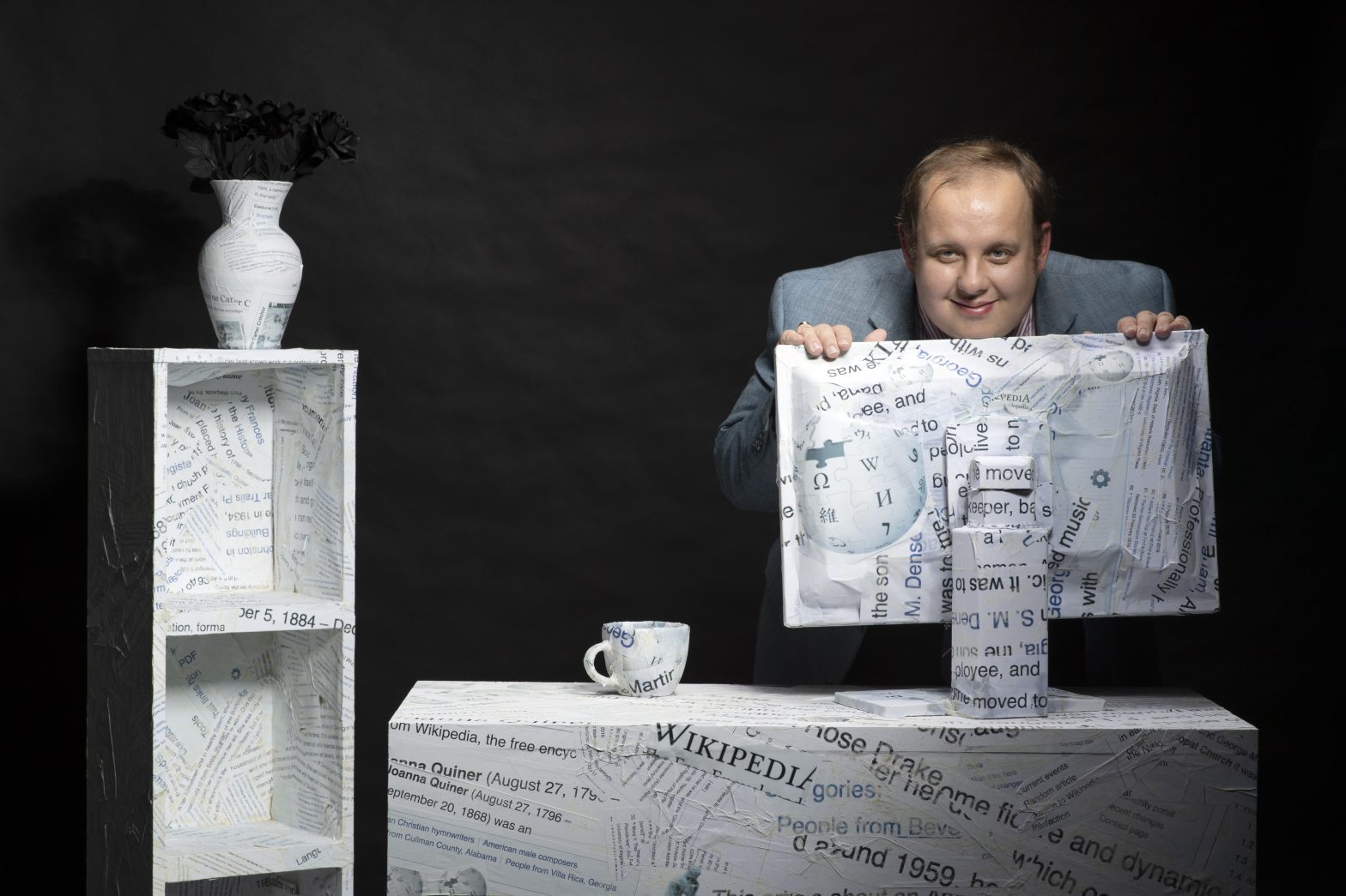 A photo of Steven Pruitt leaning over a computer monitor wrapped in Wikipedia branded paper.