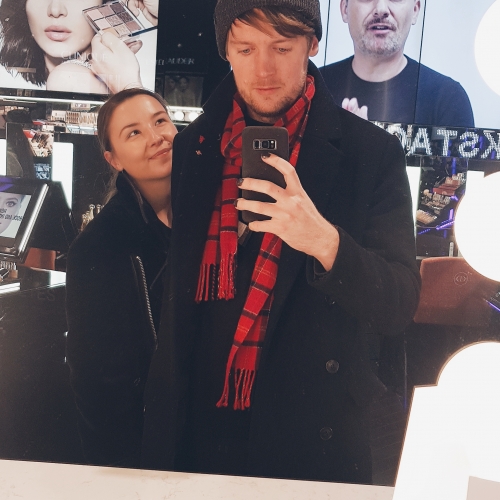 A portrait photo of coxy and Ine Vestengen in a make-up store, surrounded by bright lights and advertising for commercial brand makeups.