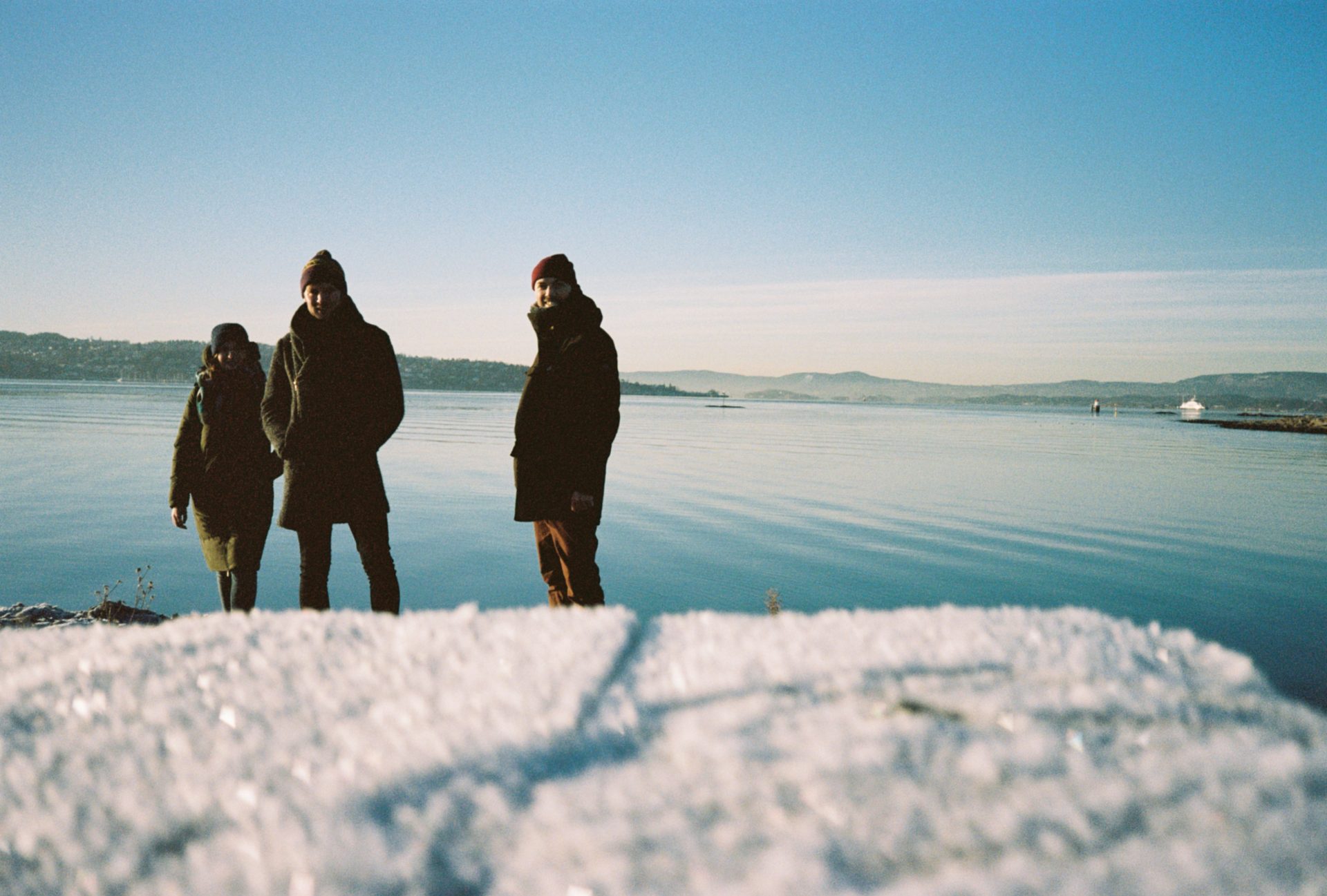 A photo of three people in front of a frozen Oslo fjord. These people are (from left to right) Iga, Matt, and Ben James Wood