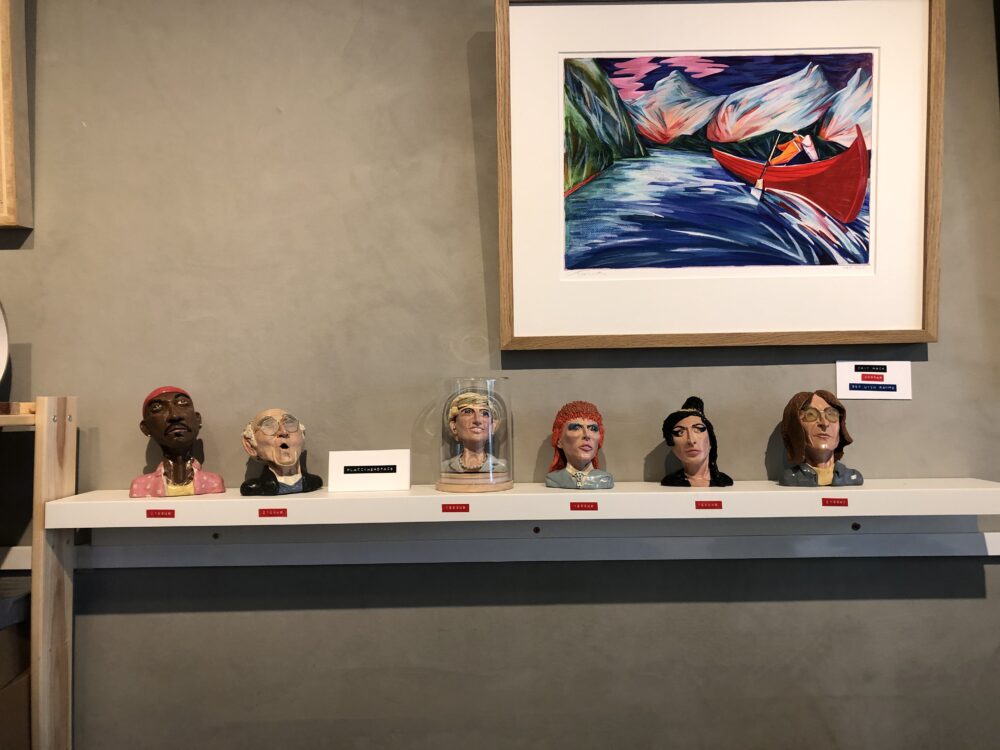 placcyheadface models on a shelf, situated below a framed print of a painting
