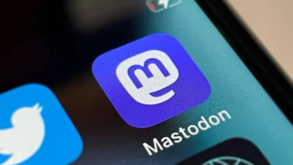 A close-up photo of a mobile phone showing the app icon of Mastodon and just out of frame, the icon for Twitter.